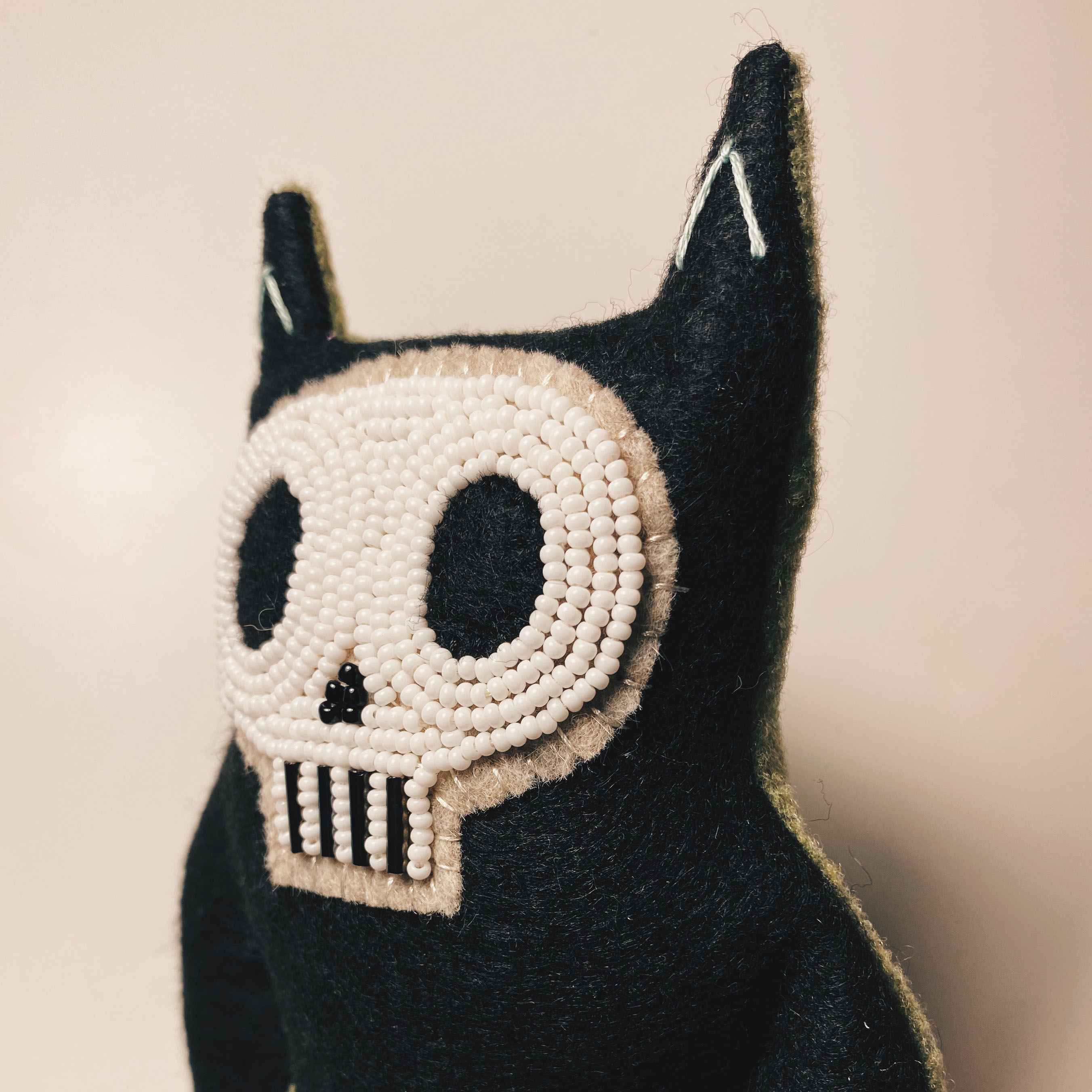 detail of hand sewn black and white catfish toy face with detailed seed beaded face.