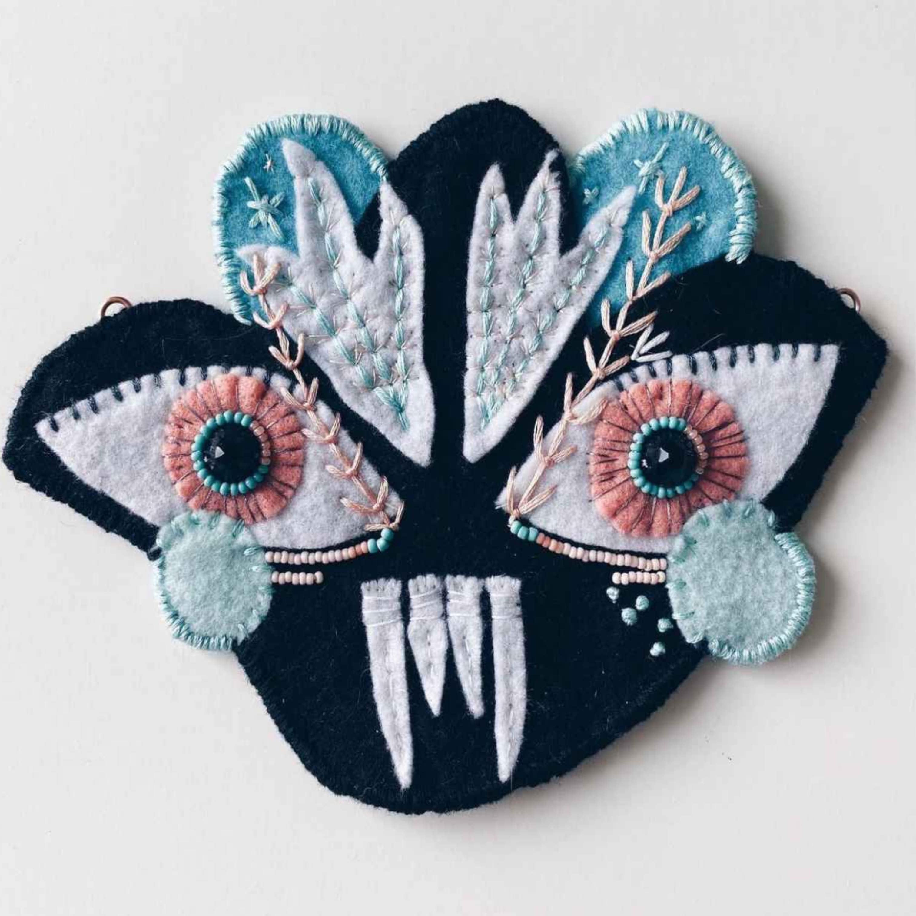 black and white embroidered vampire monster face with vines and small details.